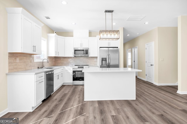 kitchen featuring visible vents, decorative backsplash, a kitchen island, appliances with stainless steel finishes, and a sink