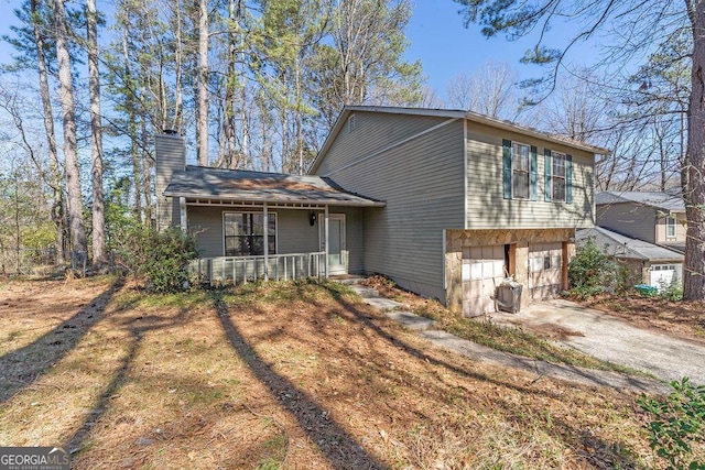 exterior space featuring a garage, driveway, a chimney, and a porch