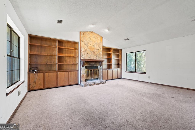 unfurnished living room featuring lofted ceiling, a textured ceiling, a fireplace, visible vents, and carpet