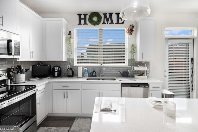 kitchen featuring stainless steel appliances, a sink, white cabinetry, light countertops, and tasteful backsplash