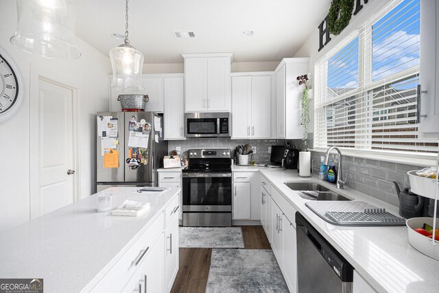 kitchen featuring stainless steel appliances, dark wood-style flooring, a sink, and light countertops