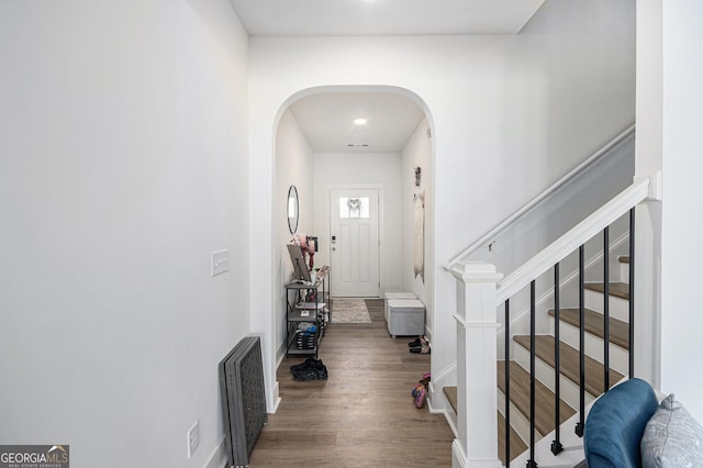 entryway with baseboards, stairs, arched walkways, and wood finished floors