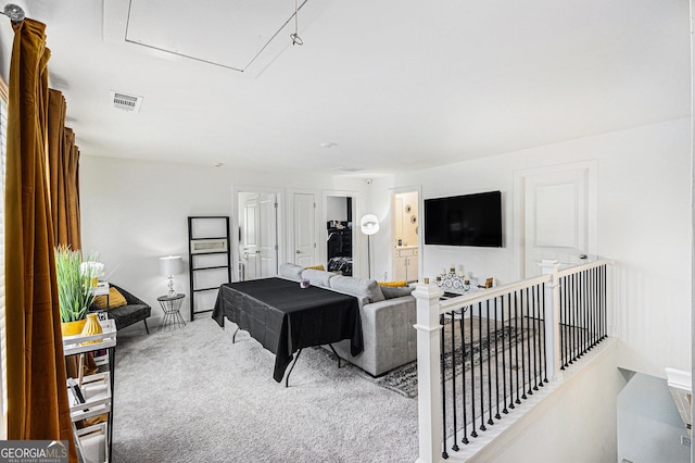 carpeted living area featuring visible vents and attic access