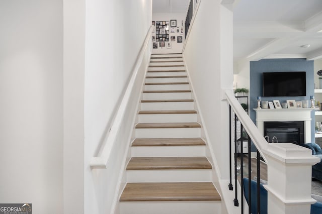 stairs featuring a fireplace, coffered ceiling, and beam ceiling