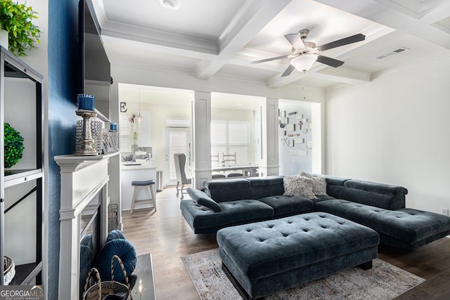 living area with coffered ceiling, wood finished floors, visible vents, a high end fireplace, and beamed ceiling