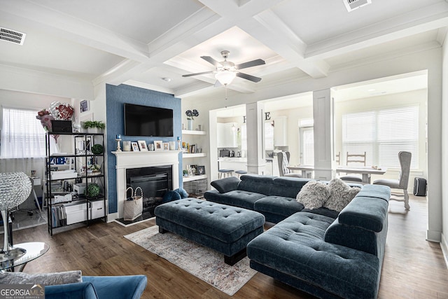 living area with a healthy amount of sunlight, visible vents, beam ceiling, and wood finished floors