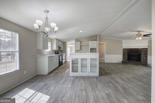 kitchen featuring light wood-style flooring, a sink, a stone fireplace, light countertops, and range