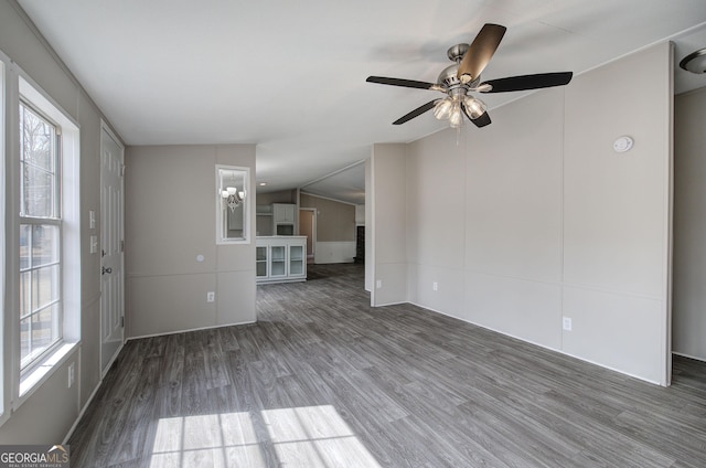 unfurnished living room with a wealth of natural light, lofted ceiling, wood finished floors, and ceiling fan