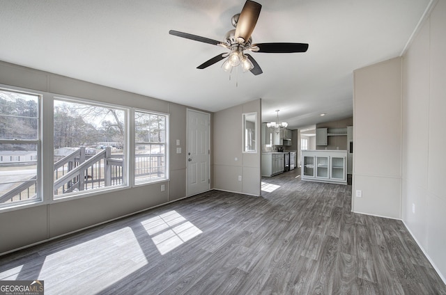 unfurnished living room with lofted ceiling, dark wood-style flooring, and ceiling fan with notable chandelier