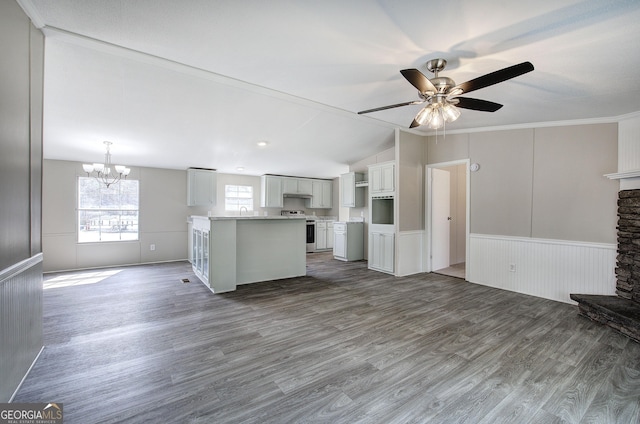 unfurnished living room featuring dark wood-style floors, a fireplace, vaulted ceiling, wainscoting, and ceiling fan with notable chandelier