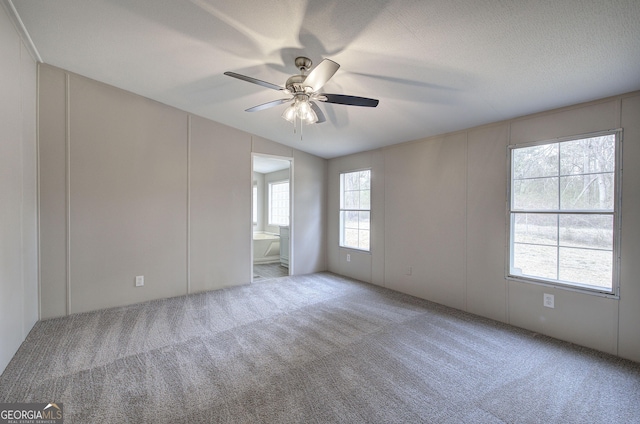 carpeted empty room featuring a textured ceiling and a ceiling fan