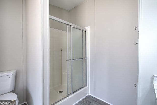 full bath featuring toilet, wood finished floors, and a stall shower