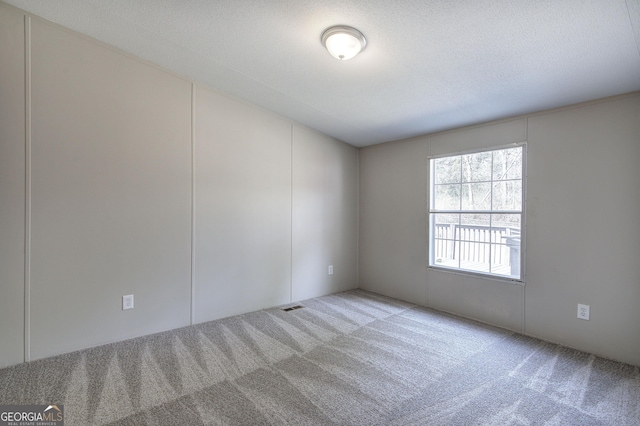 empty room with visible vents, a textured ceiling, and carpet flooring