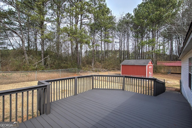 wooden terrace featuring an outdoor structure, fence, and a shed