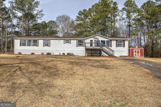 manufactured / mobile home with stairway, an outbuilding, a front lawn, and a shed