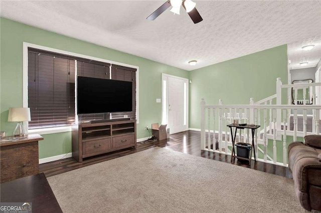 living area with a ceiling fan, a textured ceiling, baseboards, and wood finished floors