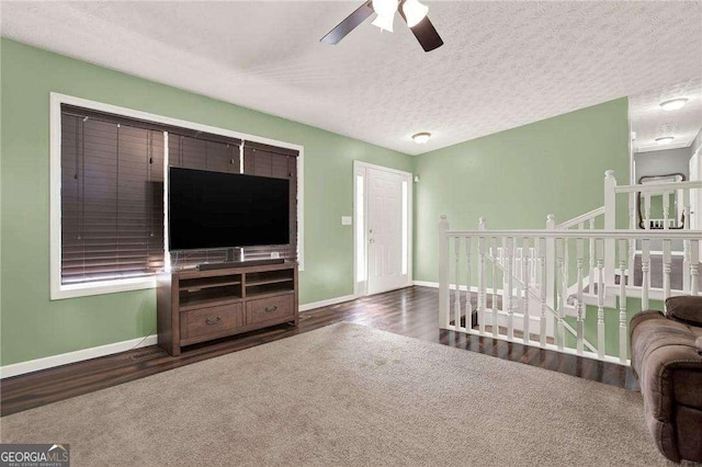 living room featuring a textured ceiling, wood finished floors, a ceiling fan, and baseboards