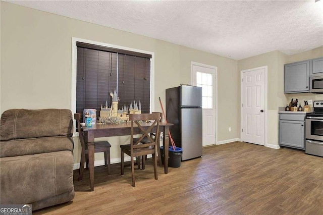 dining room featuring a textured ceiling, baseboards, and wood finished floors