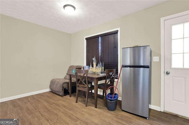 dining room featuring a textured ceiling, baseboards, and wood finished floors