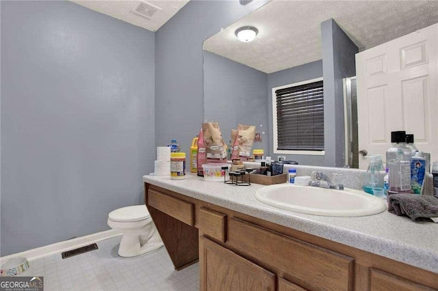 bathroom featuring toilet, a textured ceiling, vanity, and visible vents