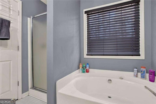 bathroom featuring a garden tub and a shower stall