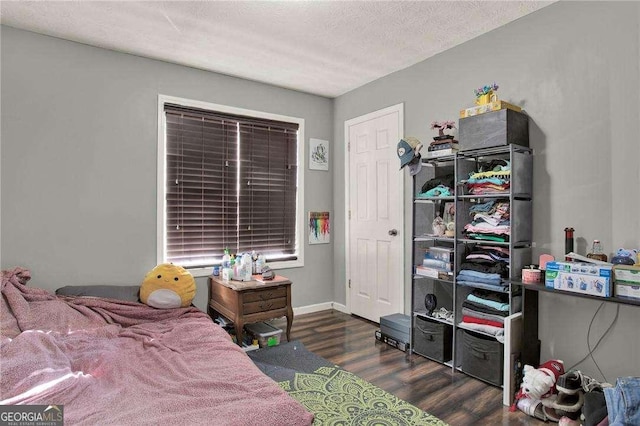 bedroom featuring a textured ceiling, dark wood-style flooring, and baseboards