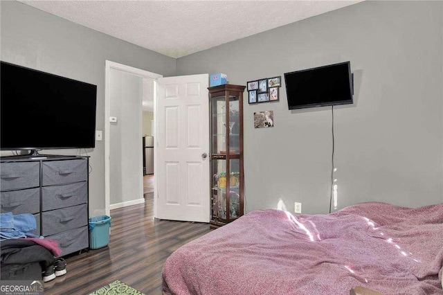 bedroom featuring a textured ceiling, baseboards, and wood finished floors