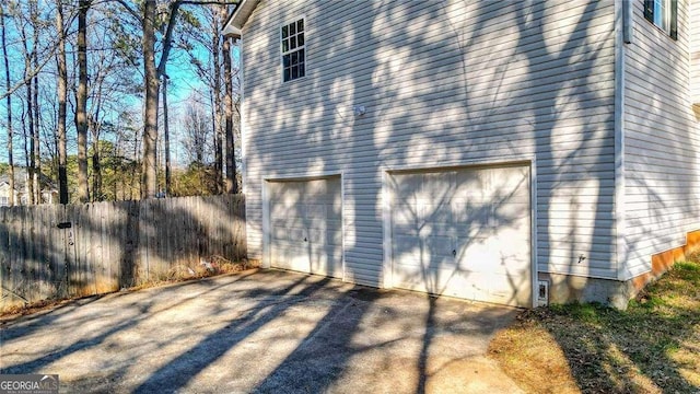 view of side of property with an attached garage and fence