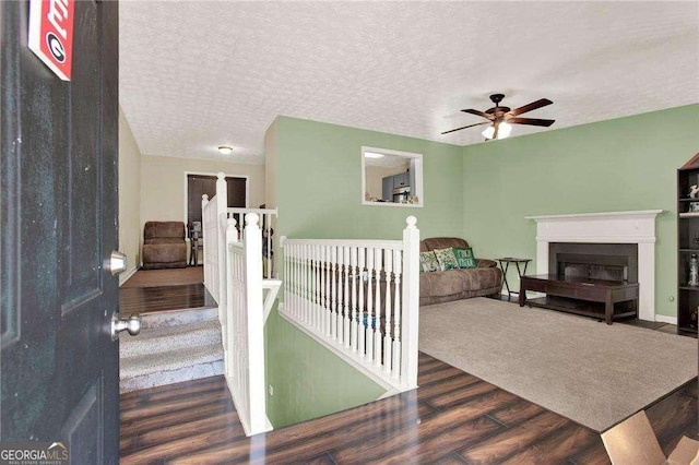 interior space with a textured ceiling, wood finished floors, and an upstairs landing