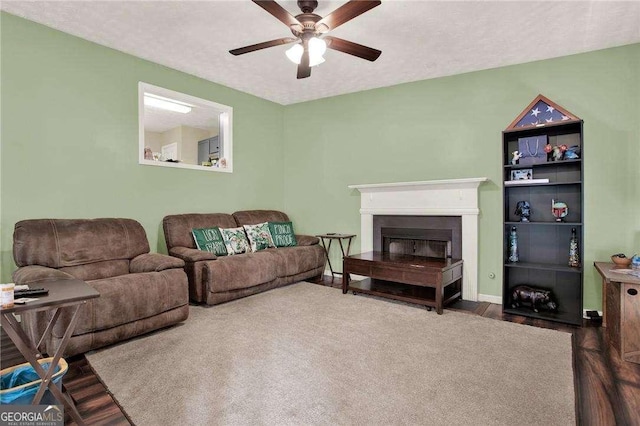 living area with baseboards, ceiling fan, wood finished floors, a textured ceiling, and a fireplace