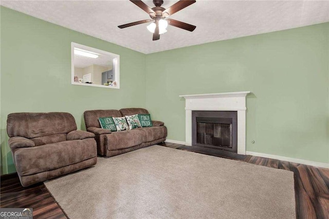 living area featuring a textured ceiling, a fireplace with flush hearth, wood finished floors, and baseboards