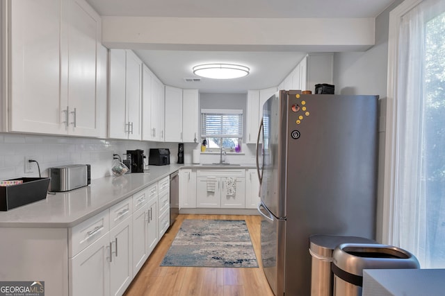 kitchen with tasteful backsplash, visible vents, appliances with stainless steel finishes, light wood-style floors, and white cabinets