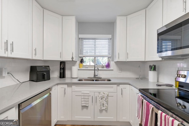 kitchen with stainless steel appliances, light countertops, a sink, and white cabinetry