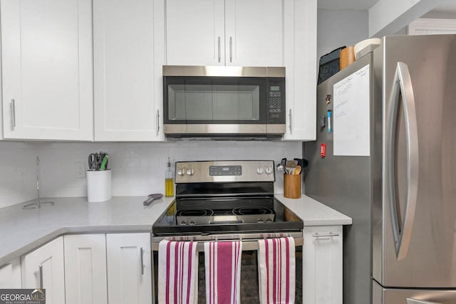 kitchen featuring stainless steel appliances, light countertops, decorative backsplash, and white cabinetry