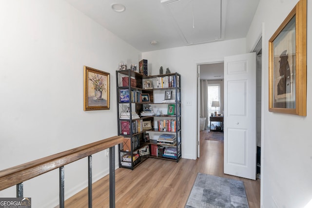 hallway with light wood-style flooring and attic access