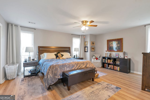 bedroom featuring multiple windows, wood finished floors, visible vents, and baseboards