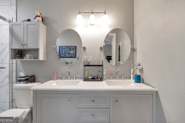 bathroom featuring double vanity, a sink, and toilet