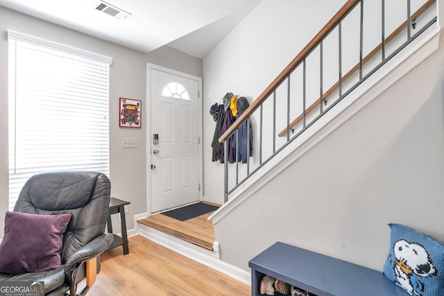 foyer featuring stairway, baseboards, visible vents, and light wood finished floors