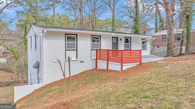 view of front of property with brick siding, covered porch, a front yard, and fence