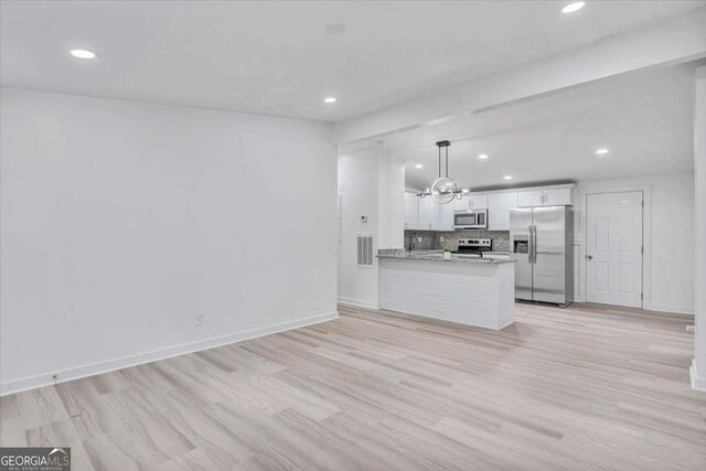 kitchen featuring light wood-style flooring, white cabinets, appliances with stainless steel finishes, decorative light fixtures, and backsplash