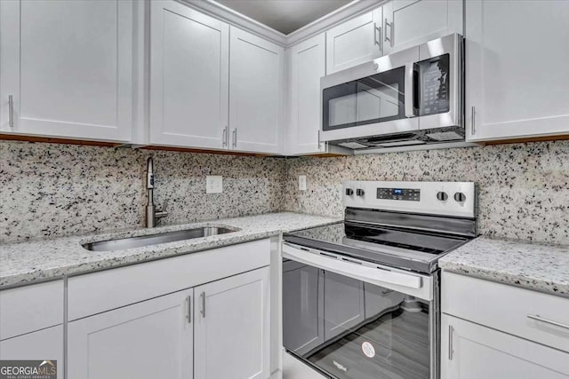 kitchen featuring a sink, stainless steel appliances, white cabinets, and decorative backsplash