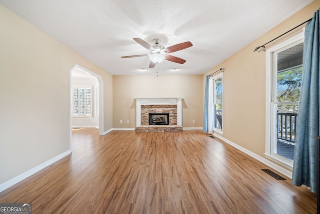 unfurnished living room featuring a fireplace, plenty of natural light, wood finished floors, and visible vents