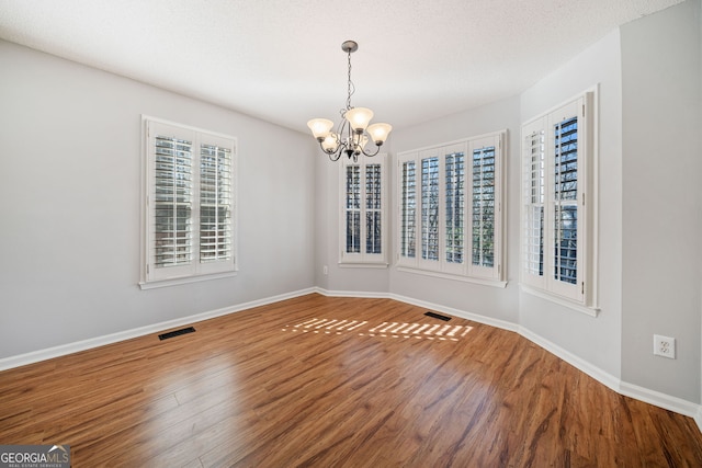 unfurnished dining area featuring baseboards, visible vents, and wood finished floors