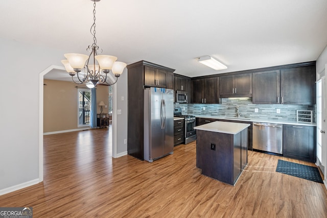 kitchen featuring dark brown cabinetry, tasteful backsplash, stainless steel appliances, light countertops, and a sink