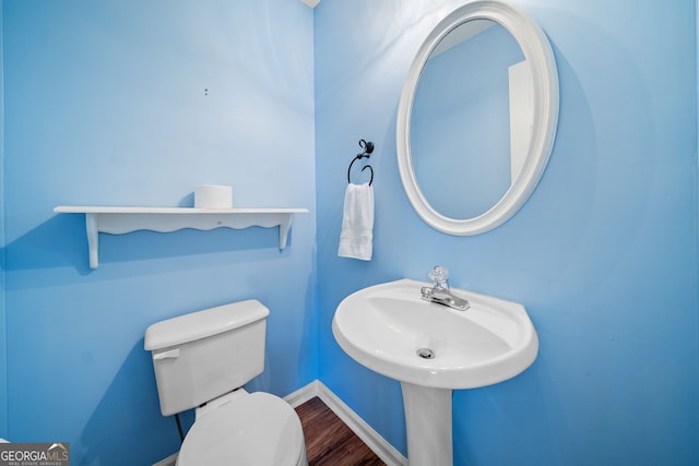 bathroom with toilet, baseboards, and wood finished floors