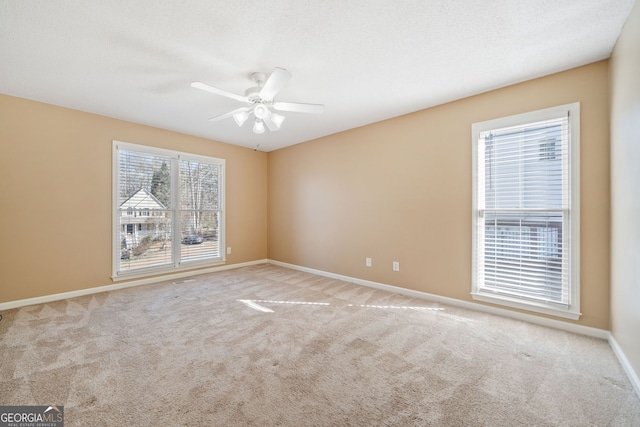 empty room with a textured ceiling, carpet, a ceiling fan, and baseboards