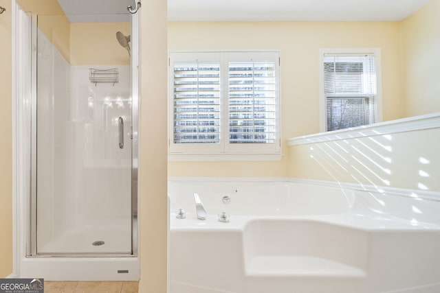 bathroom with a shower stall, a bath, and tile patterned floors