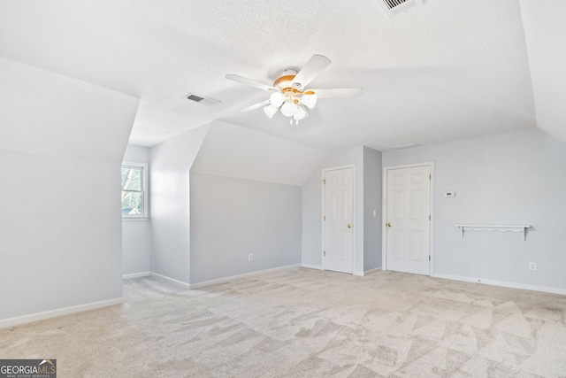 additional living space featuring light carpet, visible vents, vaulted ceiling, and a ceiling fan