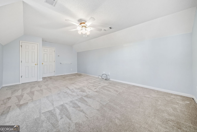 additional living space with lofted ceiling, a textured ceiling, visible vents, and a ceiling fan