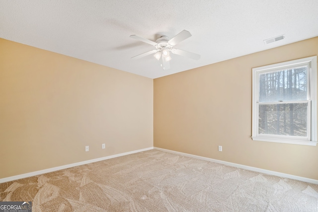 spare room featuring carpet, visible vents, a textured ceiling, and baseboards